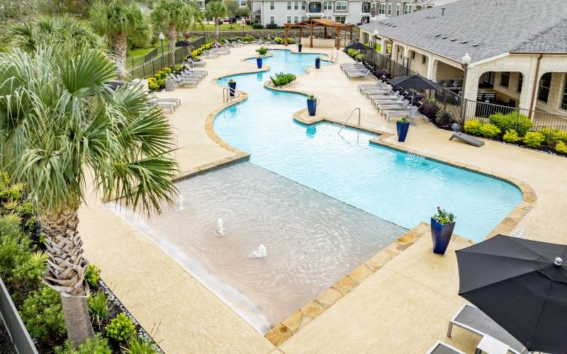 a swimming pool with a deck and trees and buildings in the background